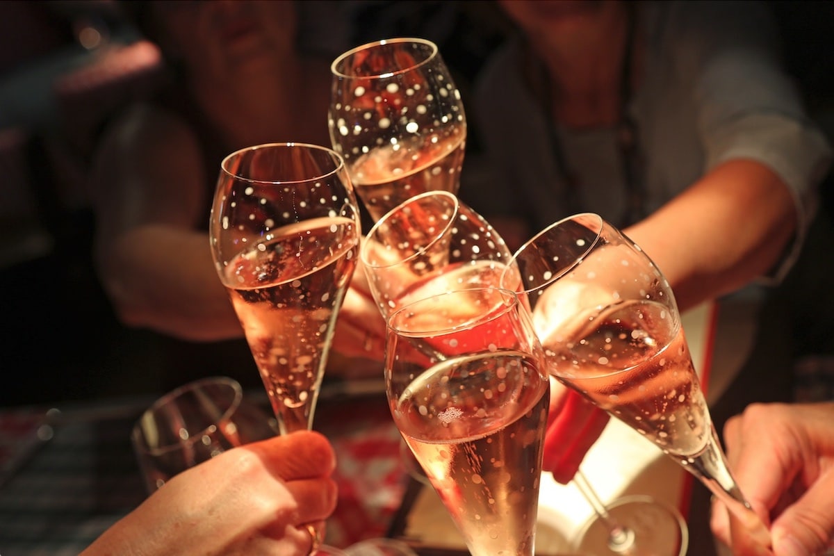 Photo of 4 hands toasting each other with full glasses of champagne