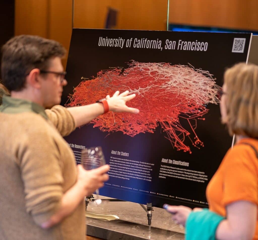 Two attendees admiring the work of Simon Porter - a poster showing a visual representation of the University of California, San Francisco